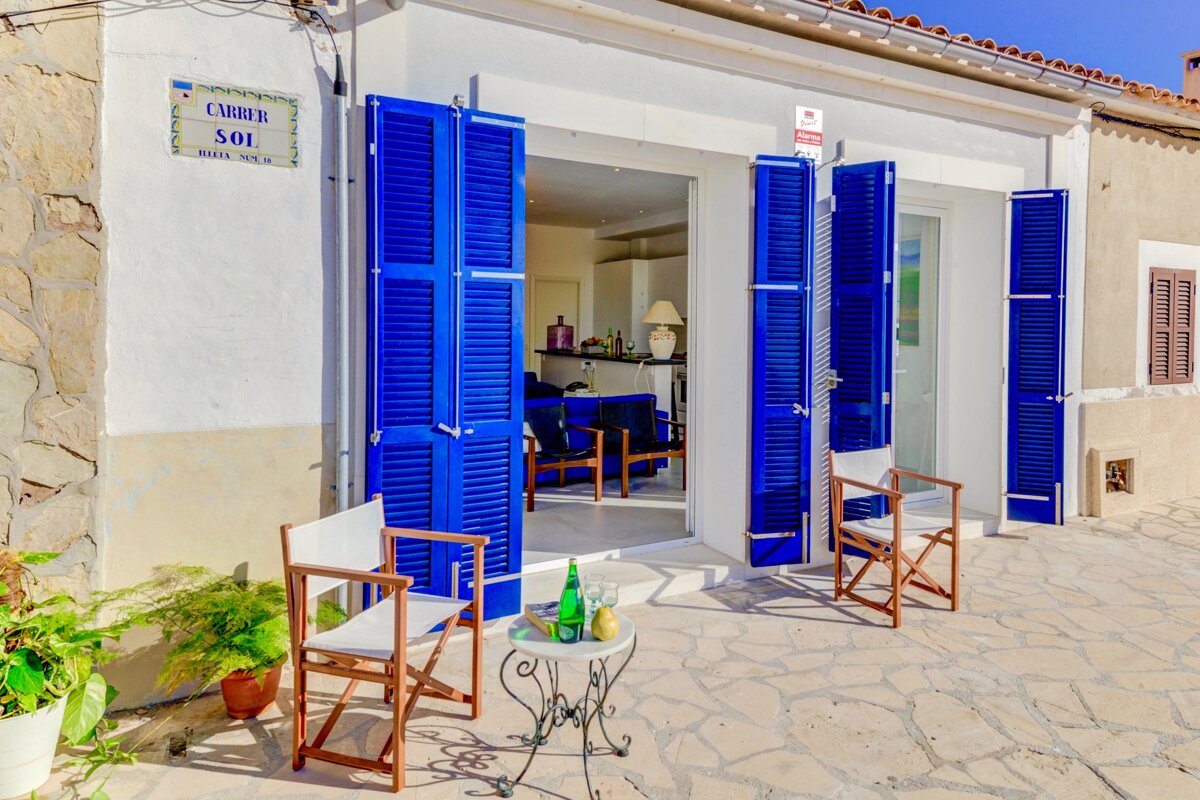 A white building with blue shutters and a sign that says carrer sol