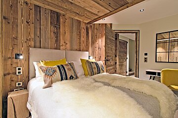 A bedroom with wood paneling and a bed with yellow pillows