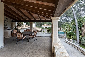 A patio with a table and chairs under a wooden roof