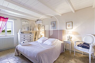 A bedroom with a purple headboard and a white chair