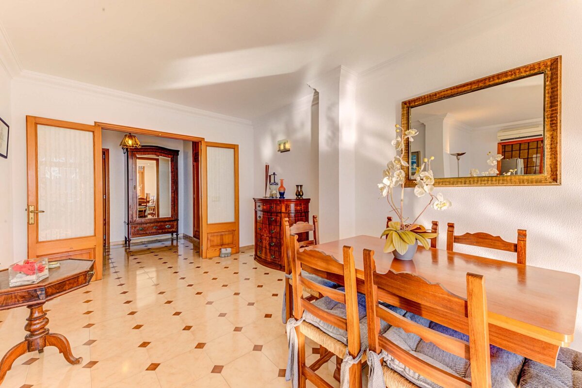 A dining room with a table and chairs and a mirror