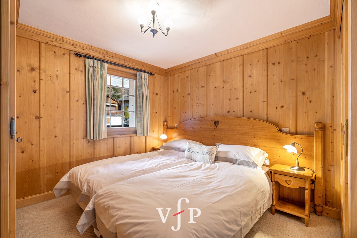 A bedroom with wood paneled walls and a bed with a pillow that says