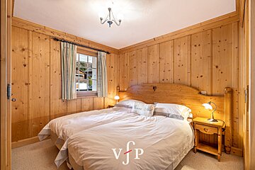 A bedroom with wood paneled walls and a bed with a pillow that says