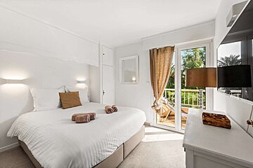 A bedroom with a large bed and a balcony