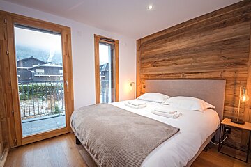 A bedroom with a large bed and a balcony