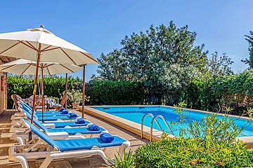 A swimming pool with blue chairs and umbrellas