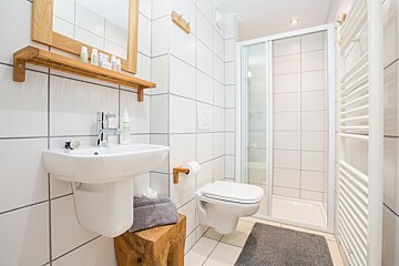 A bathroom with white tiles and a toilet and sink