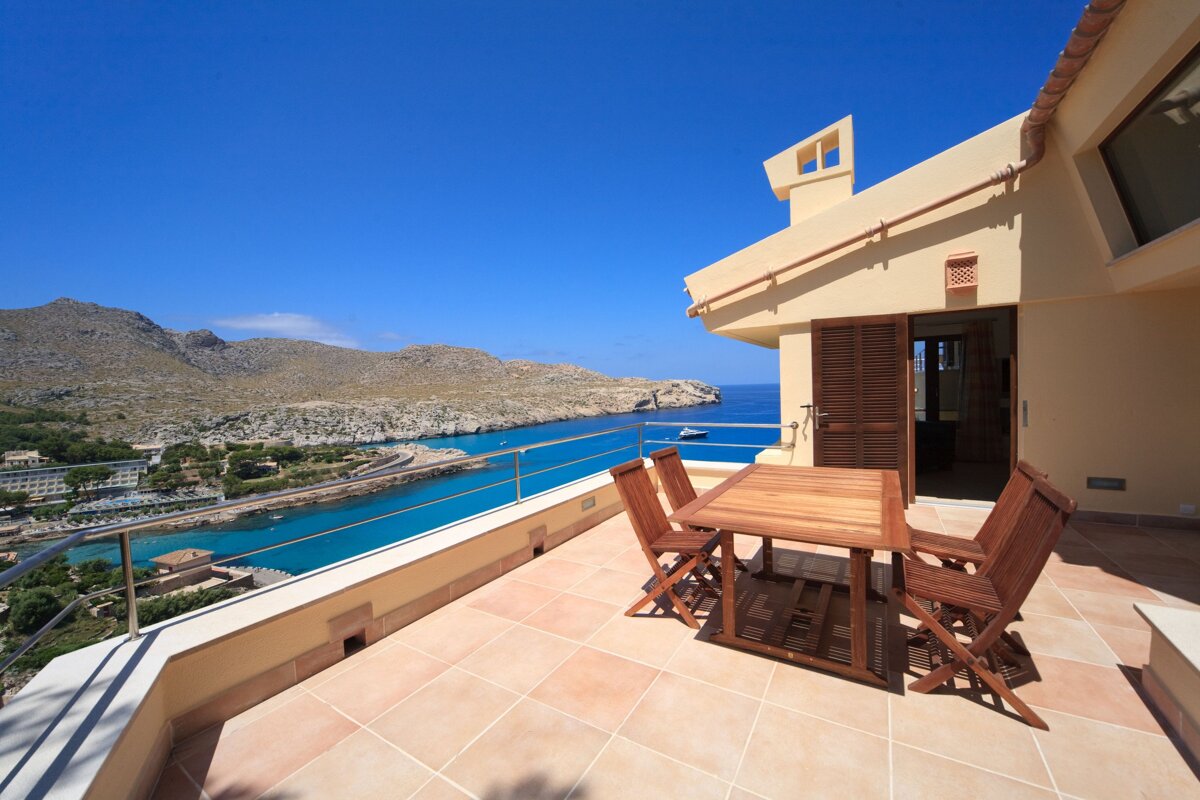 A balcony with a table and chairs overlooking the ocean