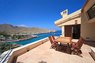 A balcony with a table and chairs overlooking the ocean