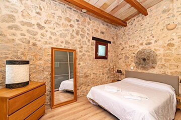 A bedroom with a stone wall and a large bed