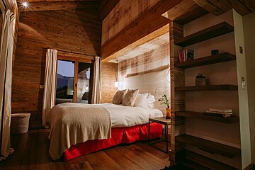 A bedroom with a bed and a shelf with books on it