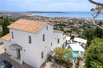 A white house with a pool and a view of the ocean