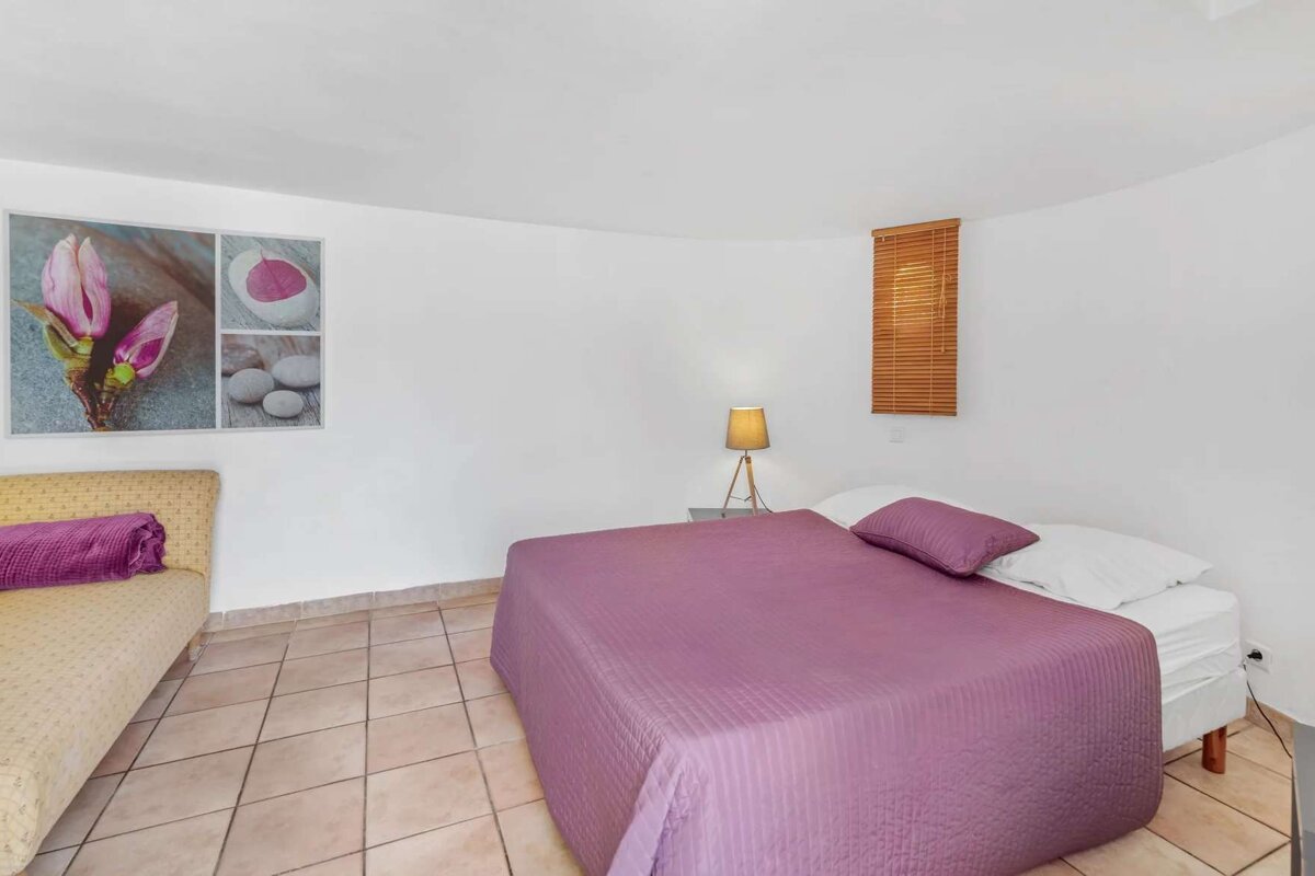 A bedroom with a purple bed and a lamp
