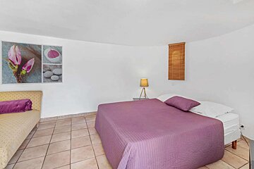 A bedroom with a purple bed and a lamp