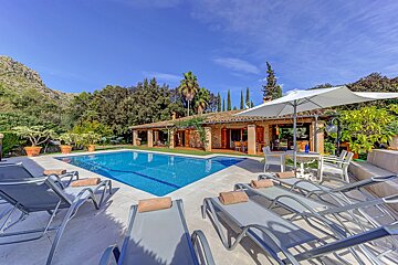 A large swimming pool is surrounded by lounge chairs and umbrellas