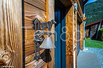 A bell with a cow on it hangs on a wooden door