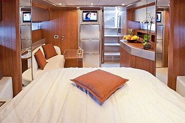A bedroom with a large bed and a television on the wall