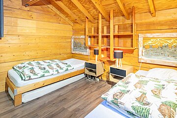 A bedroom in a log cabin with two beds and two nightstands