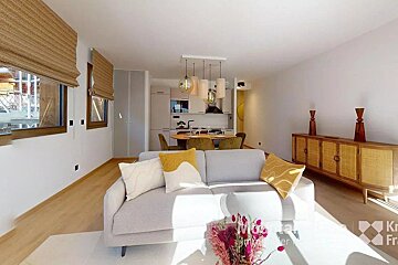 A living room with a couch and a dining room in the background