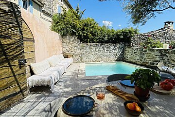 A table with a glass of wine and a loaf of bread in front of a swimming pool