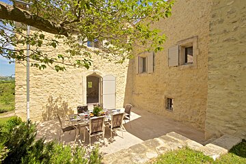 A patio with a table and chairs in front of a stone building