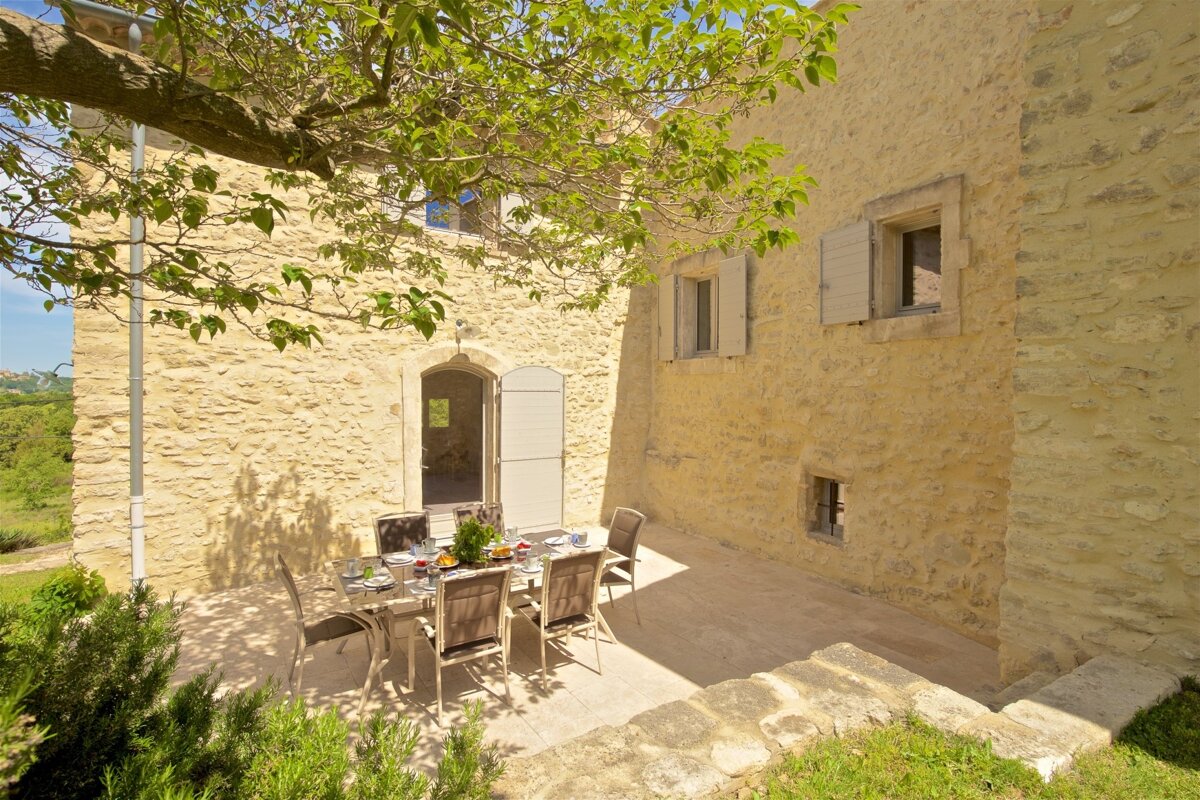 A patio with a table and chairs in front of a stone building