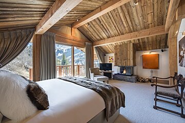 A bedroom with a large bed and a fireplace