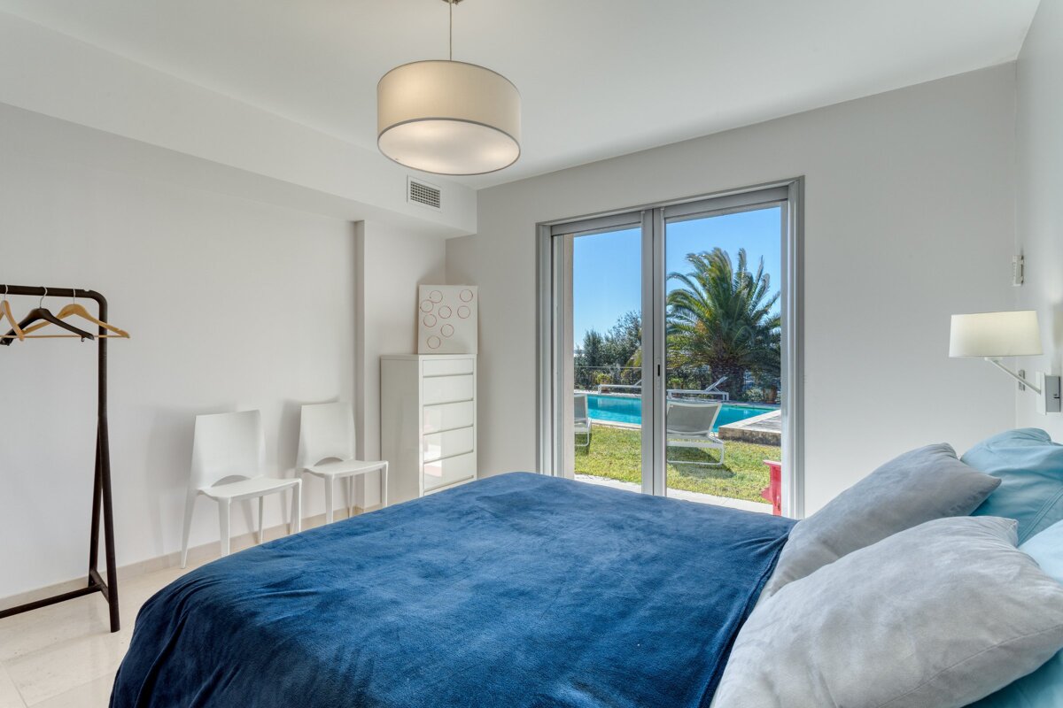 A bedroom with a blue blanket and a view of a pool