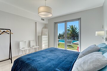 A bedroom with a blue blanket and a view of a pool