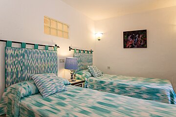 A bedroom with two beds and a painting on the wall