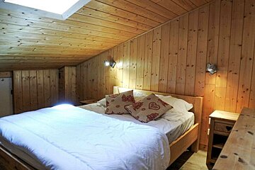 A bedroom with a bed and two pillows with hearts on them