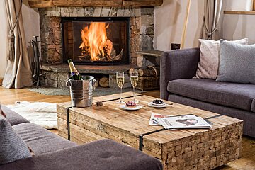 A bottle of champagne sits in a bucket on a coffee table in front of a fireplace