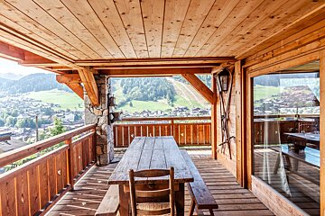 A rocking chair sits outside of a wooden cabin