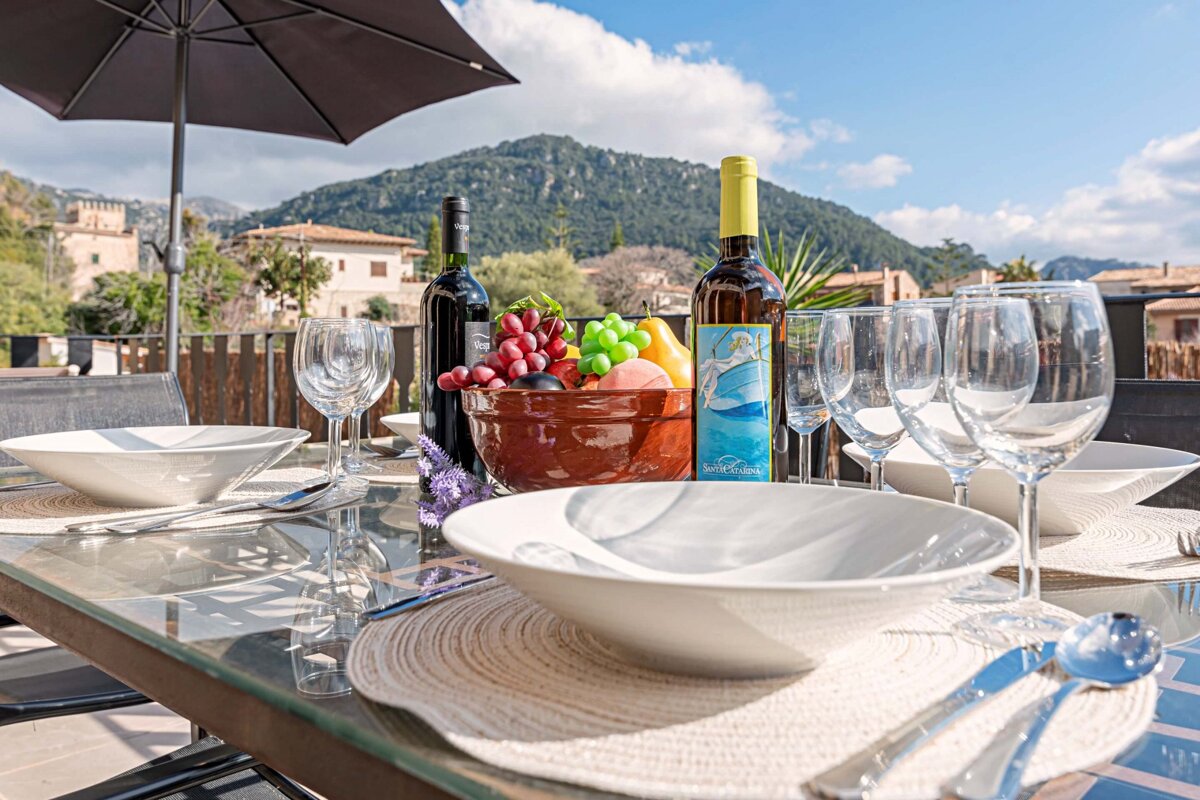 A bowl of fruit sits on a table next to a bottle of wine