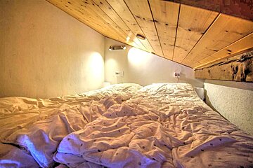 A bed with white sheets and a wooden ceiling