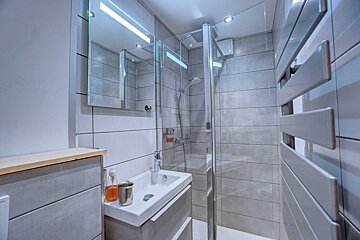 A bathroom with a sink a mirror and a walk in shower