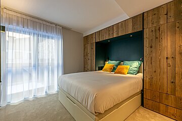 A bedroom with a large bed and wooden cabinets