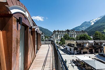A balcony overlooking a city with mountains in the background