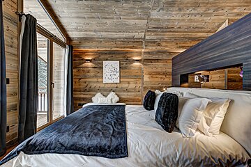 A bedroom with a wooden wall and a large bed