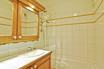 A bathroom with a sink a mirror and a shower