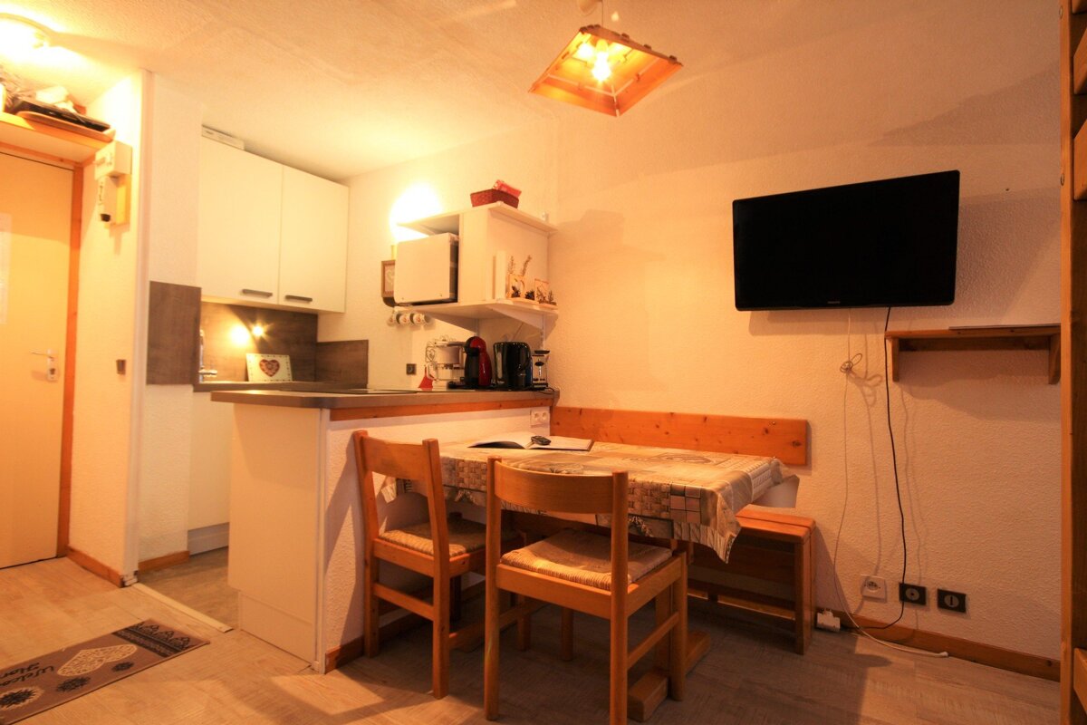 A kitchen with a table and chairs and a flat screen tv