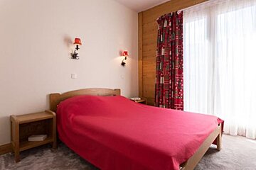 A bedroom with a red bed and red curtains