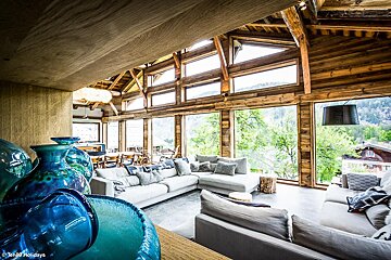 A living room with a lot of windows and a blue vase in the foreground