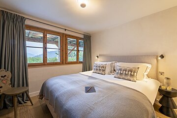 A bedroom with a large bed and two windows