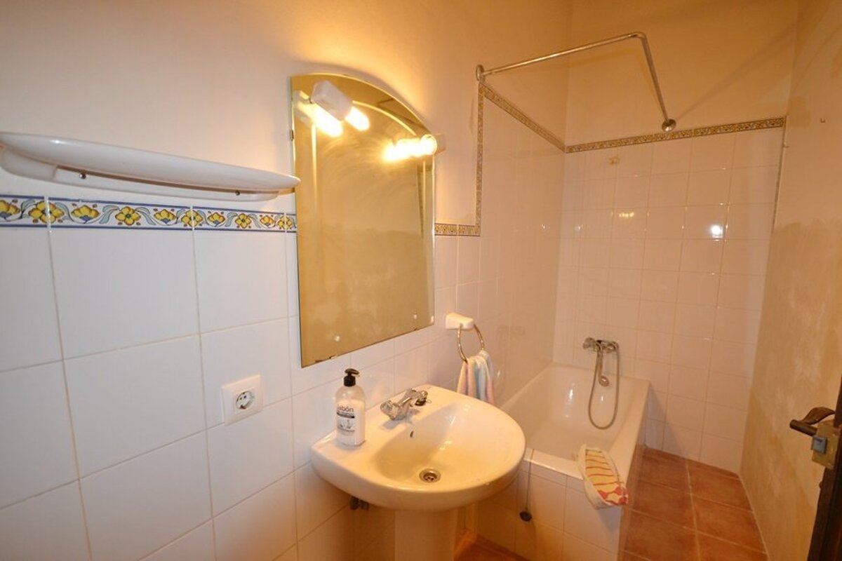 A bathroom with a sink and a bottle of shampoo on the counter