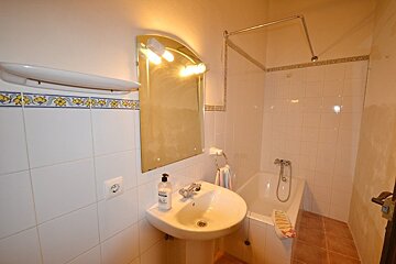 A bathroom with a sink and a bottle of shampoo on the counter