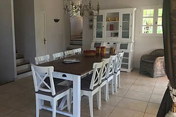 A dining room with a long table and white chairs