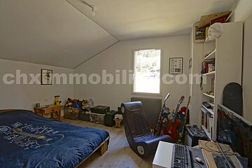 A bedroom with a bed and a chair and the website chximmobilier.com