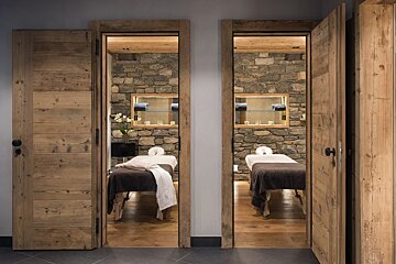 Two massage tables in a room with stone walls
