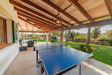 A donic ping pong table sits under a wooden roof